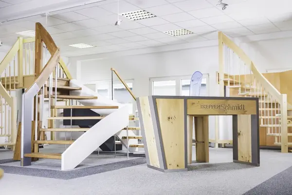 Moderne Treppenausstellung mit Holztreppen und Empfangstresen im hellen Showroom.