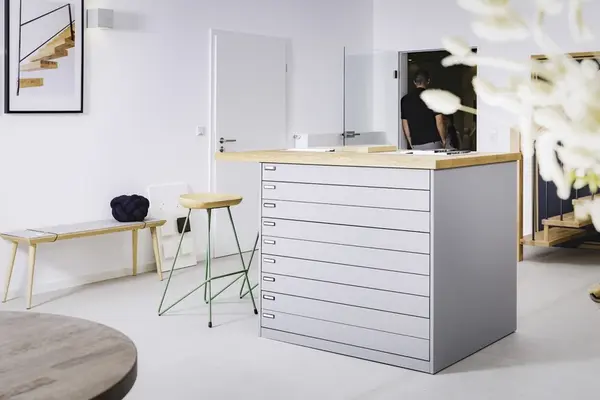 Modernes, helles Büro mit großem Schubladenschrank und minimalistischer Einrichtung.