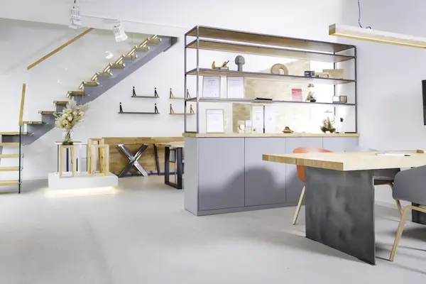 Modernes, helles Büro mit minimalistischer Einrichtung, offener Regalwand und Designer-Treppe.