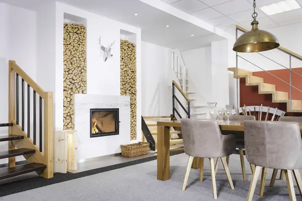 Modernes Wohnzimmer mit Kamin, Holzstapel, Esstisch und offener Treppe im skandinavischen Stil.