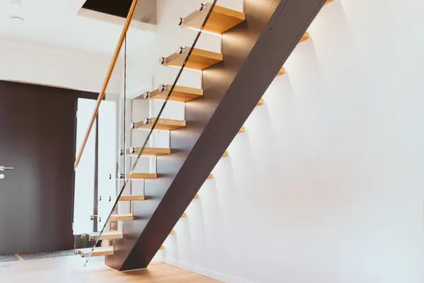 Moderne offene Holztreppe mit Glasgeländer in einem hellen, minimalistischen Flur.