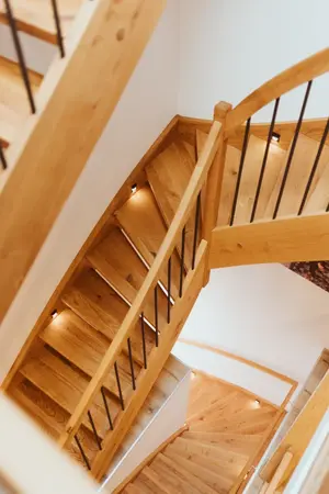 Moderne Holztreppe mit Metallgeländer und integrierter LED-Beleuchtung im Wohnhaus.