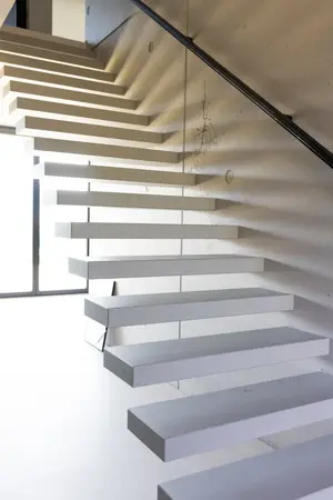 Moderne freischwebende Treppe mit weißen Stufen in minimalistischem Wohninterieur.
